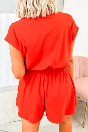 Red cotton romper with elastic waist and short sleeves.