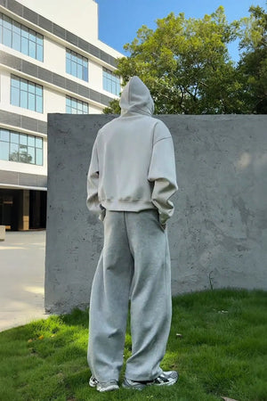 Light gray oversized slouch hoodie with kangaroo pocket and wide-leg sweatpants.