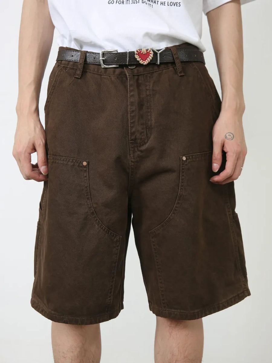 Dark brown denim carpenter shorts with utility pockets and button closure.