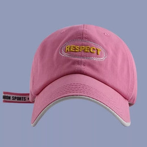 Pink baseball cap with embroidered "RESPECT" detail and side strap.