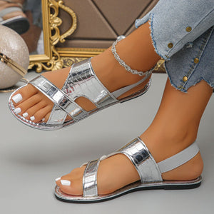 Silver crocodile-embossed open-toe sandals with criss-cross straps and elastic back.