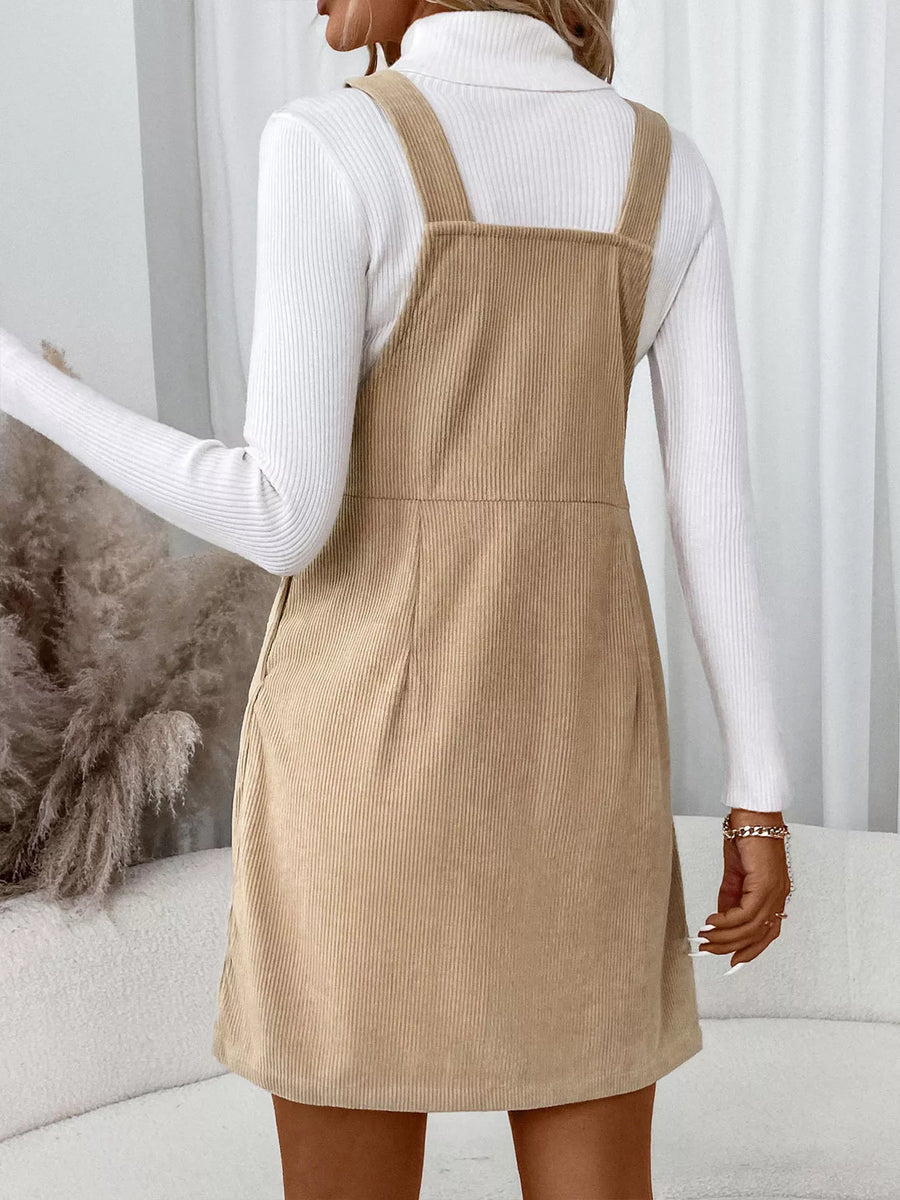 Chic tan corduroy overall dress with a square neckline and adjustable straps.
