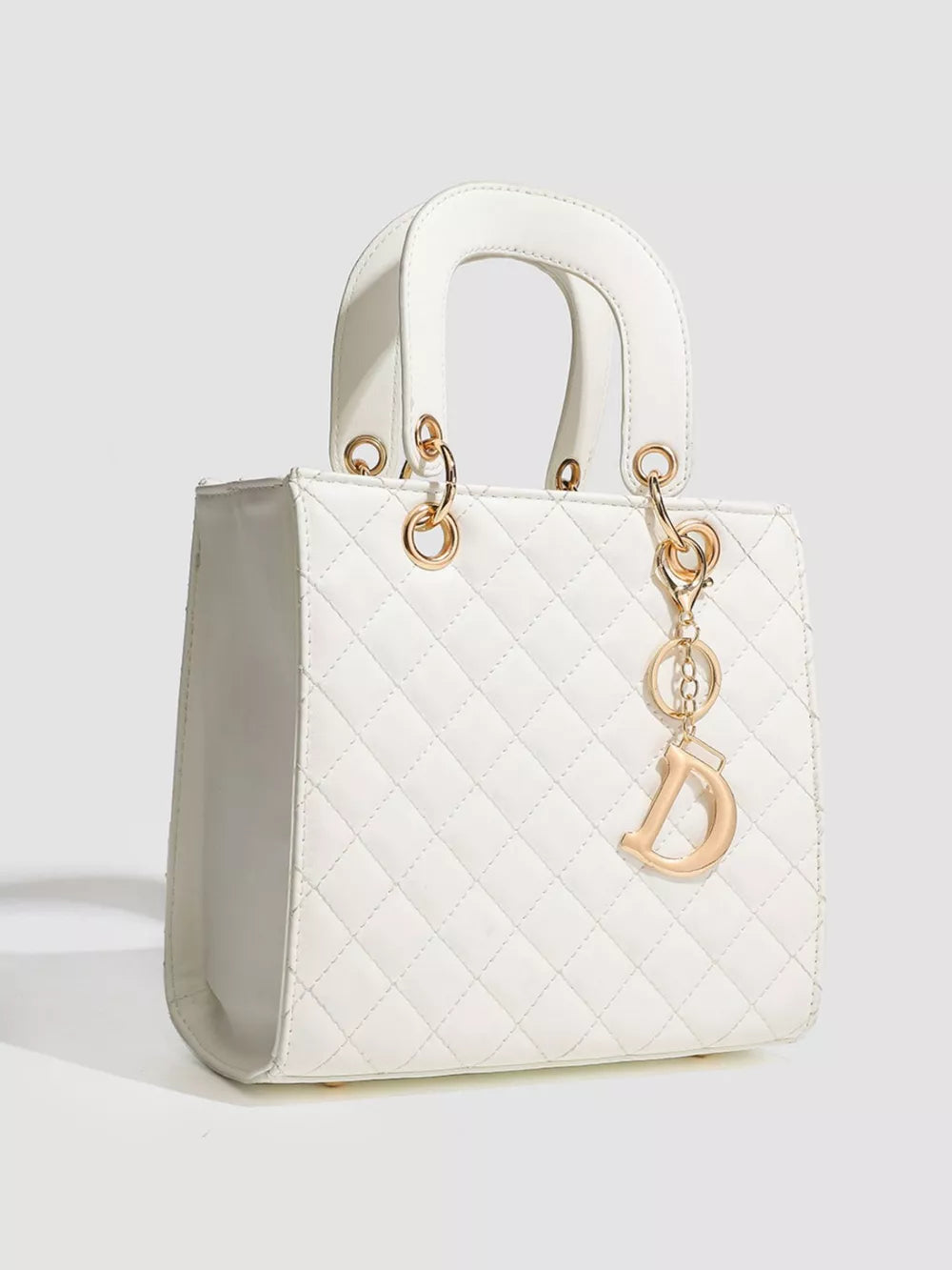 White quilted mini top-handle tote bag with gold hardware and a decorative charm.
