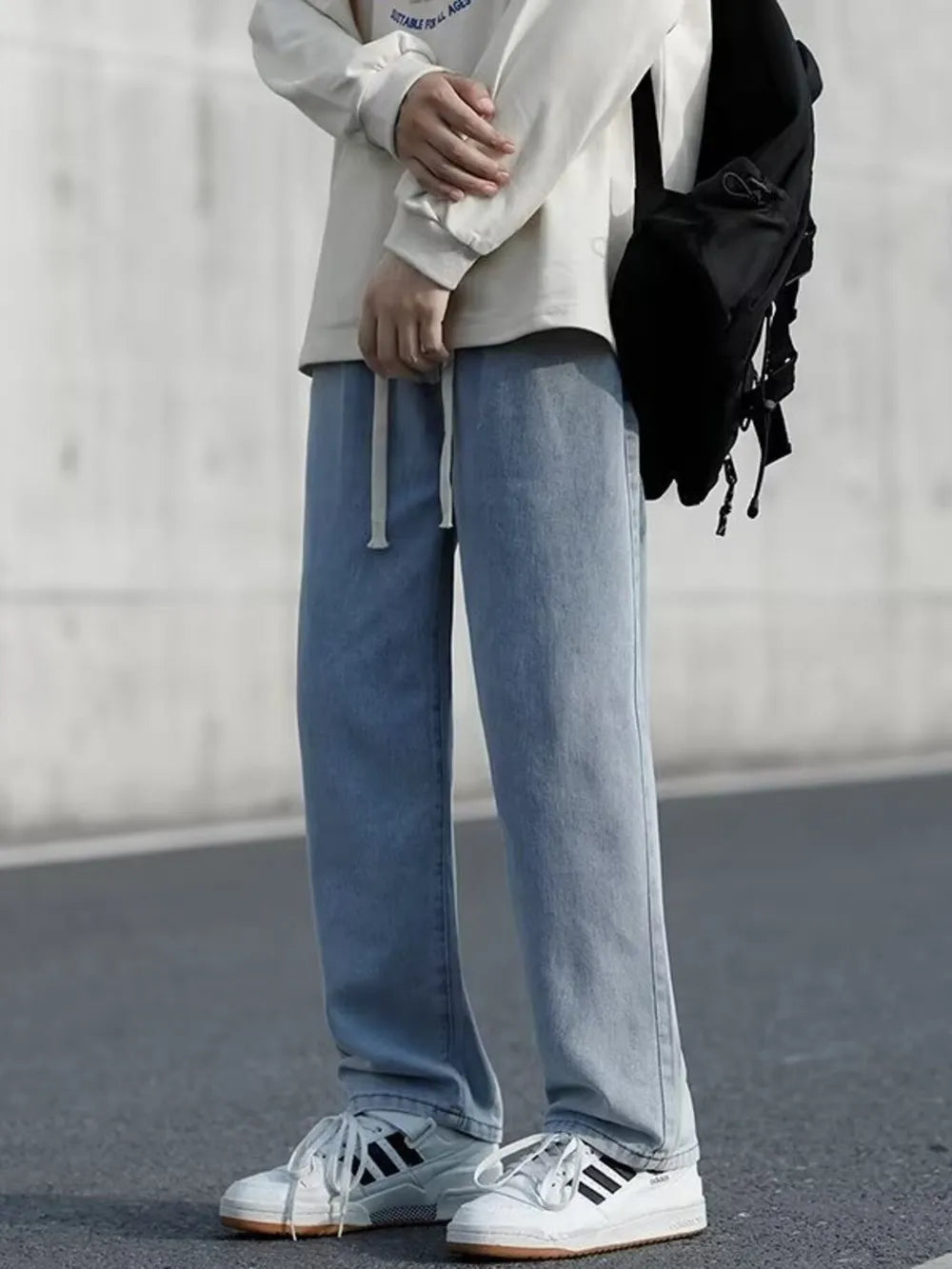 Men's light blue loose-fit jeans with drawstring waist and pockets.