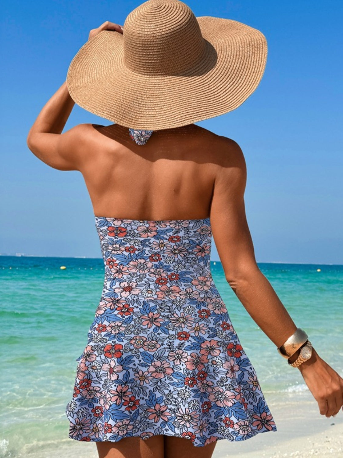 Floral print swimdress in Dusty Blue with a twisted cutout detail, strapless neckline, and ruffled hem.