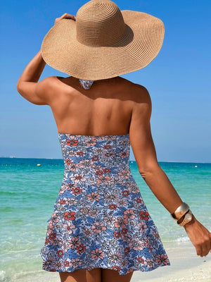 Floral print swimdress in Dusty Blue with a twisted cutout detail, strapless neckline, and ruffled hem.