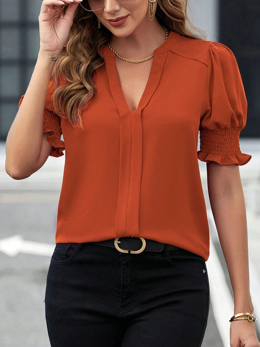 Orange shirred sleeve plunge neck blouse with v-neck and cinched cuffs.