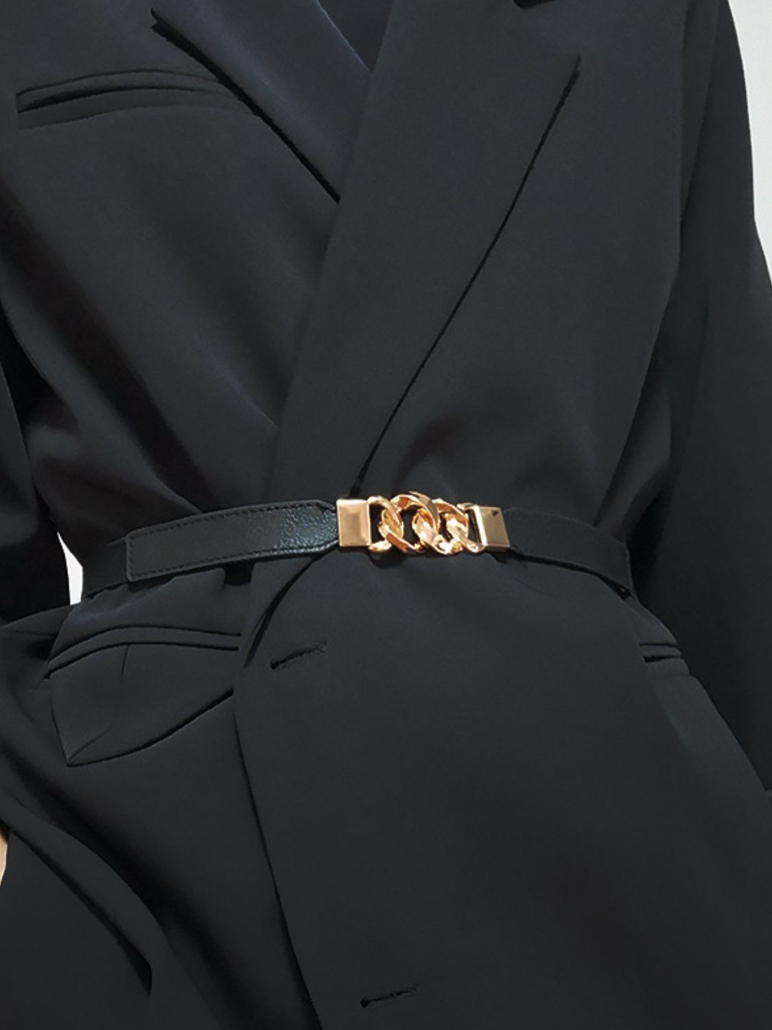 Black faux leather belt with gold chain detail and buckle accent