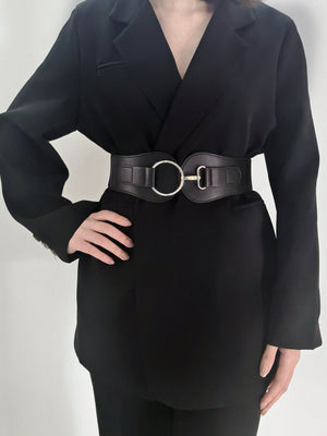 Black cincher belt with silver buckle detail worn over a blazer.