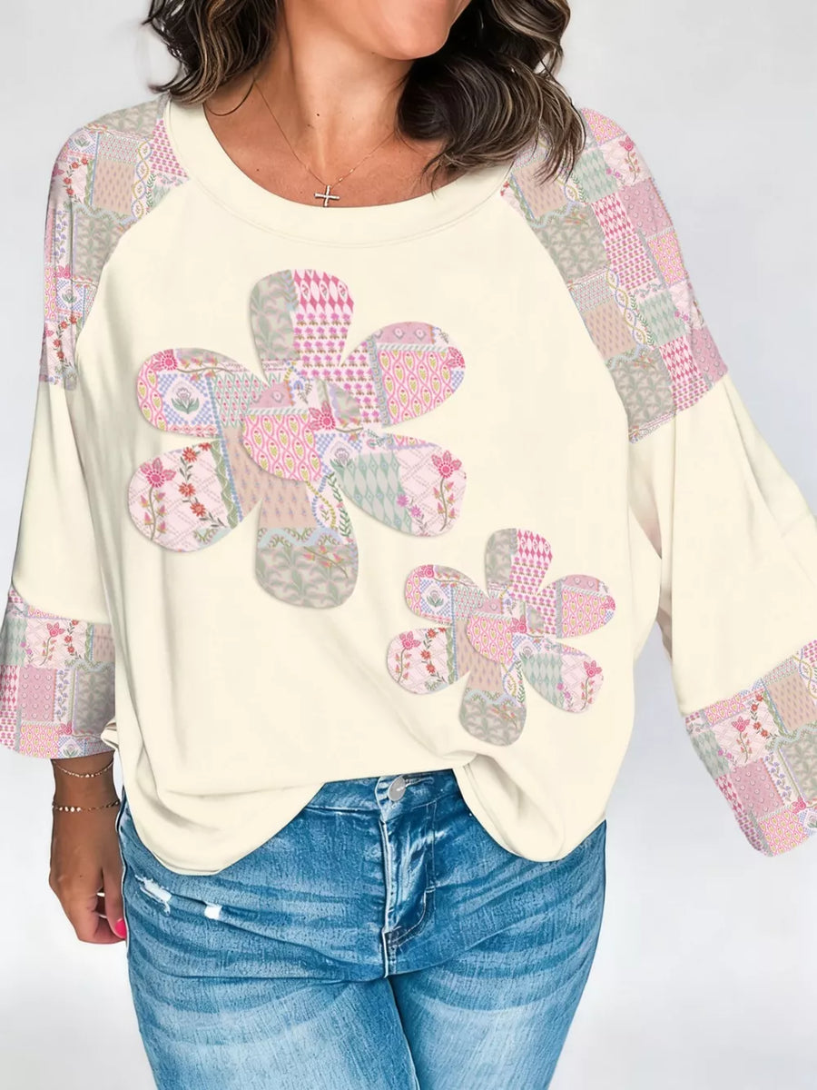Cream long-sleeve shirt with patchwork floral appliques and raglan sleeves.