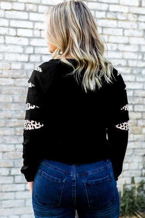 Black sweatshirt with cutout sleeves featuring a leopard print detail.