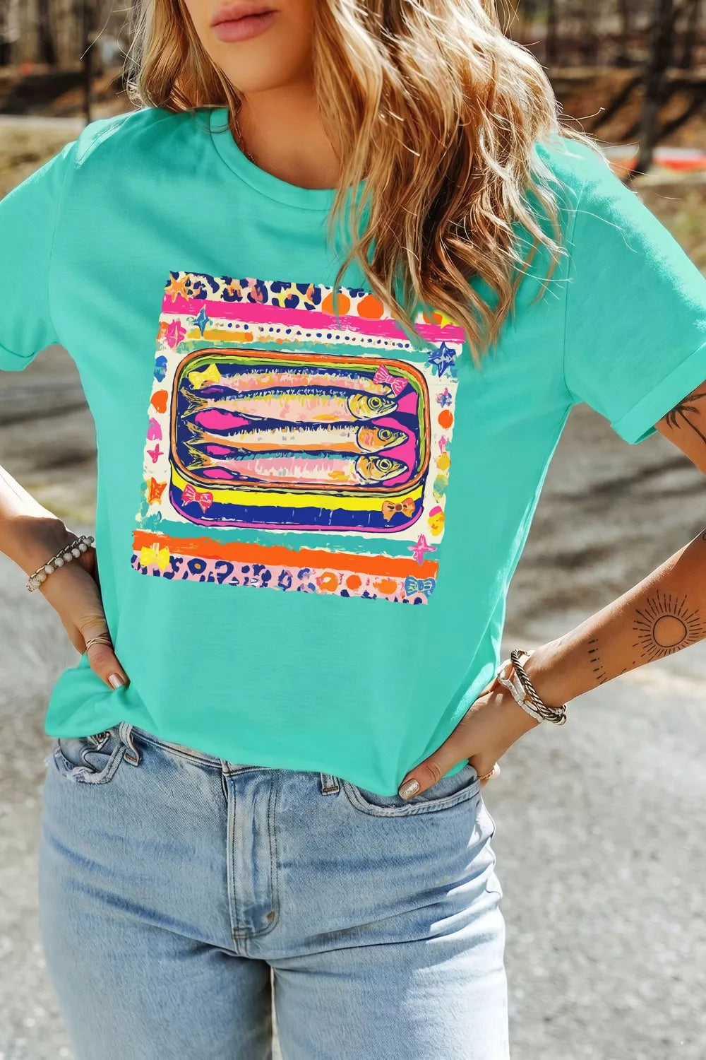 Teal cotton crew neck t-shirt with a playful sardine can graphic and colorful abstract border.