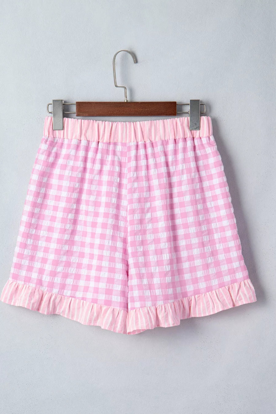 Pink gingham cotton shorts with ruffle hem and drawstring waist.