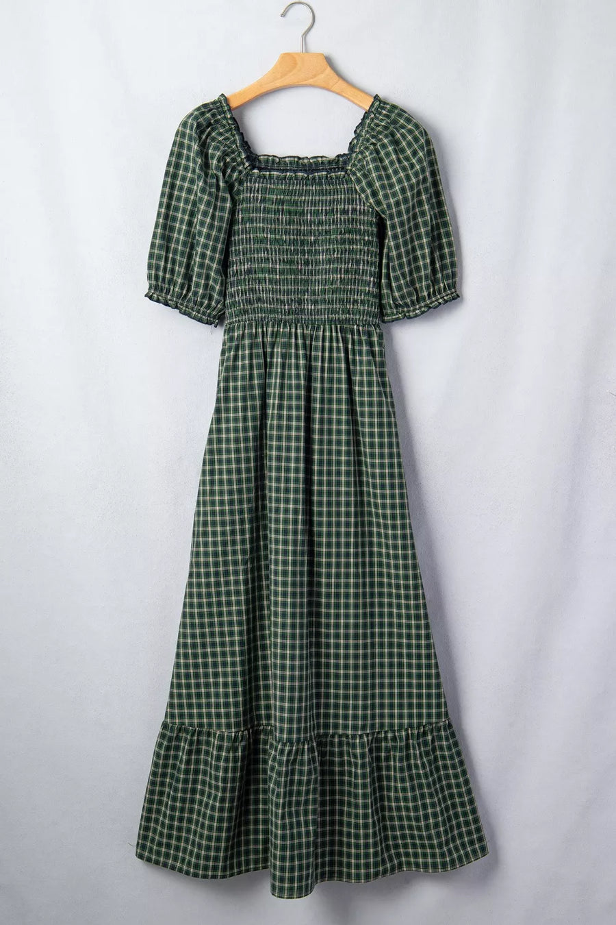 Green plaid maxi dress with smocked bodice, square neck, puff sleeves, and ruffled hem.
