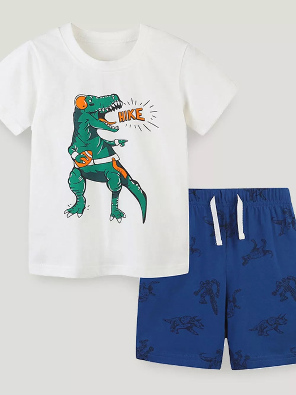 White t-shirt with dinosaur graphic and blue shorts with dinosaur print.