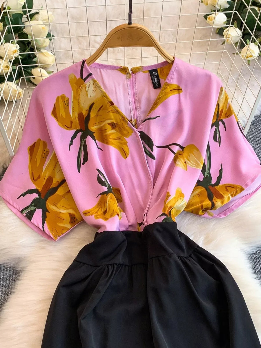 Pink abstract floral print wide-leg romper with black skirt and pockets