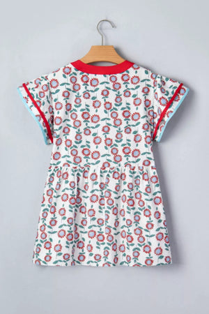 White cotton blouse with vibrant floral print, ruffle sleeves, and contrast trim.
