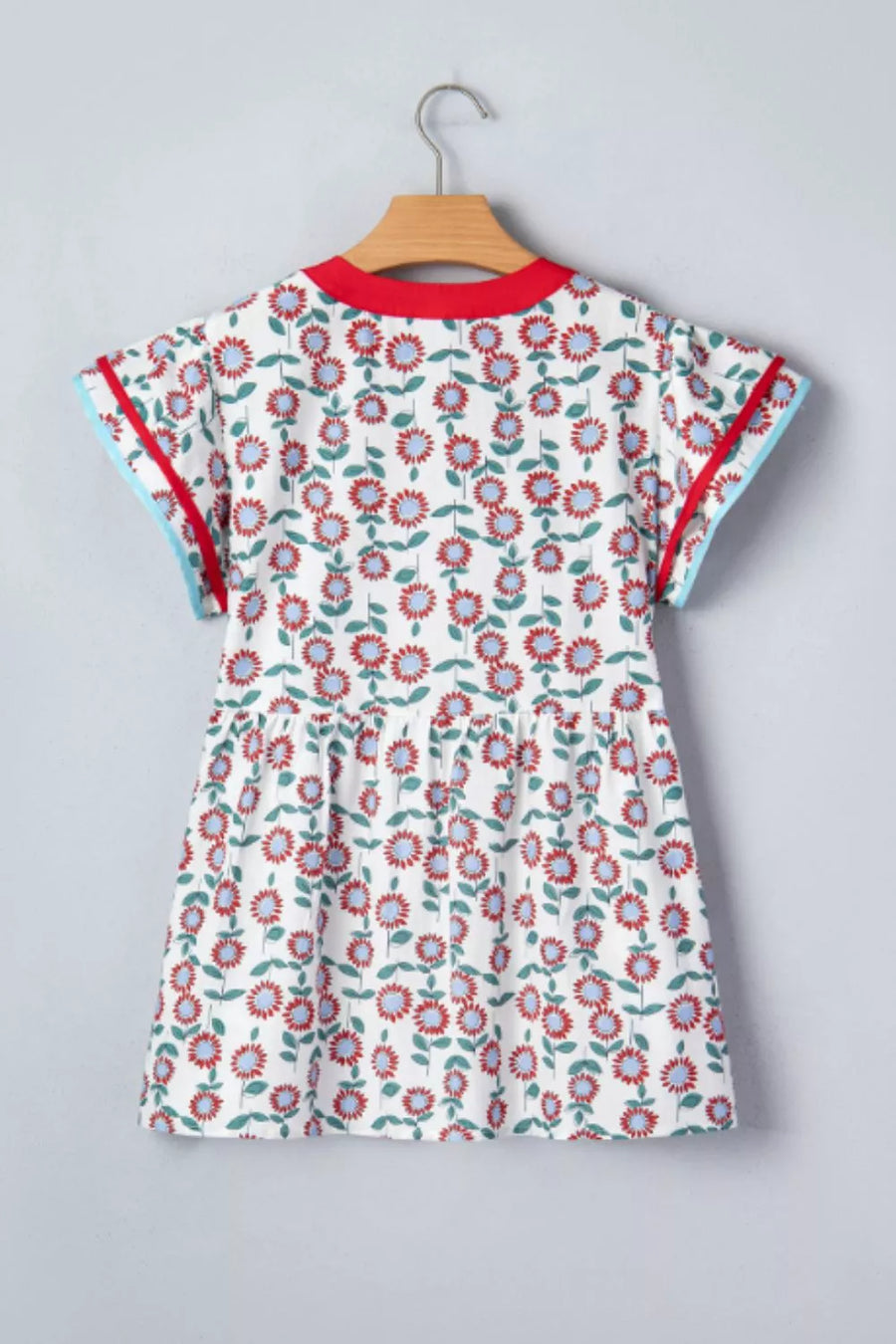 White cotton blouse with vibrant floral print, ruffle sleeves, and contrast trim.