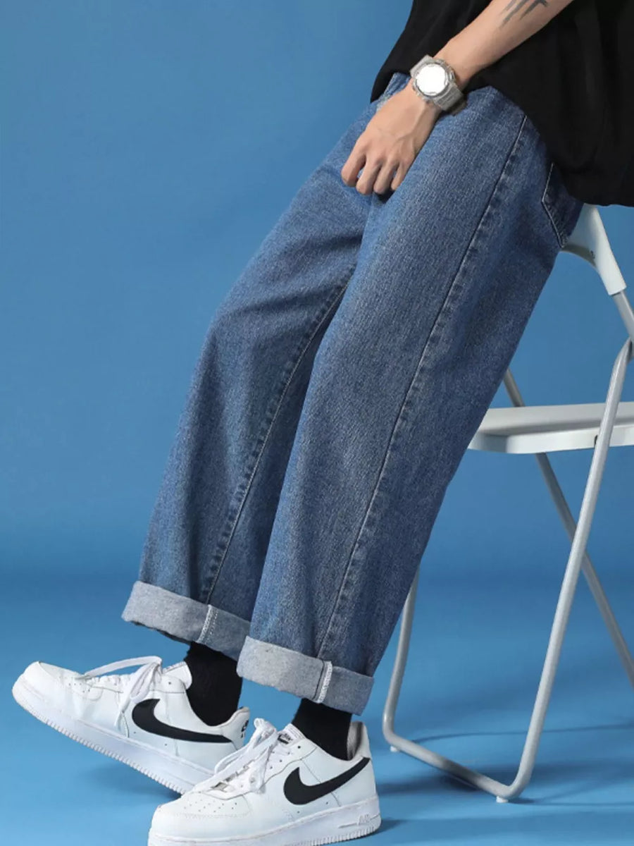 Men's light wash denim jeans with cuffed hems and a relaxed fit.