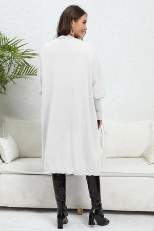 White long cardigan with balloon sleeves and pockets, styled with black boots