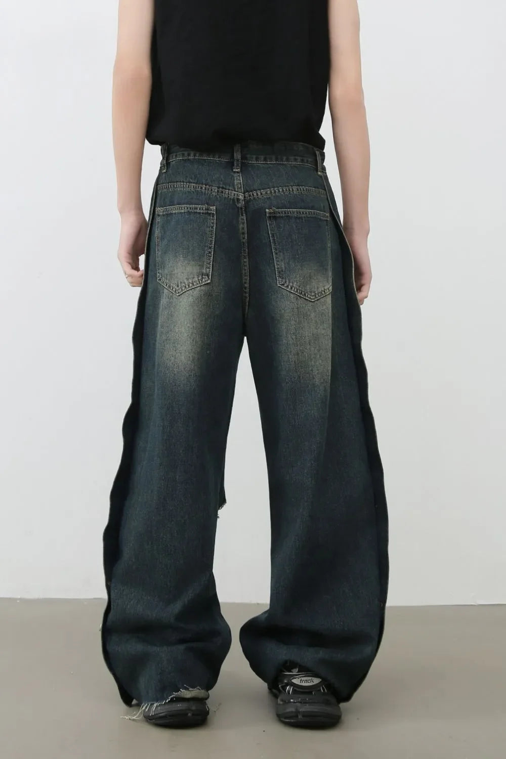 Distressed dark wide leg denim jeans with side slits and raw hems.