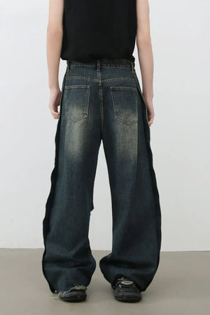 Distressed dark wide leg denim jeans with side slits and raw hems.