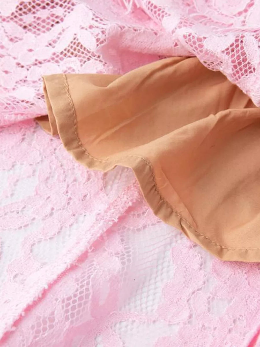 Pink lace dress with pearl embellishments and a tan lining detail.