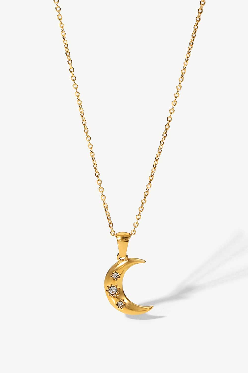 Gold crescent moon pendant necklace with three small star-shaped zirconia accents.