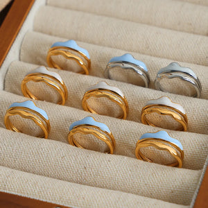 Sculpted enamel wave rings in gold, silver, light blue, and white.