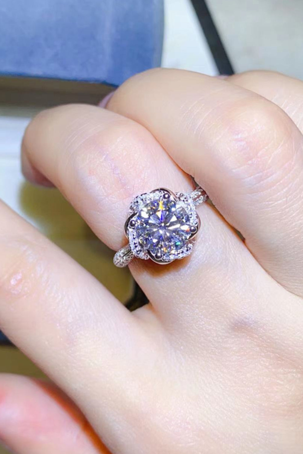 Silver floral halo moissanite engagement ring with a bright center stone.