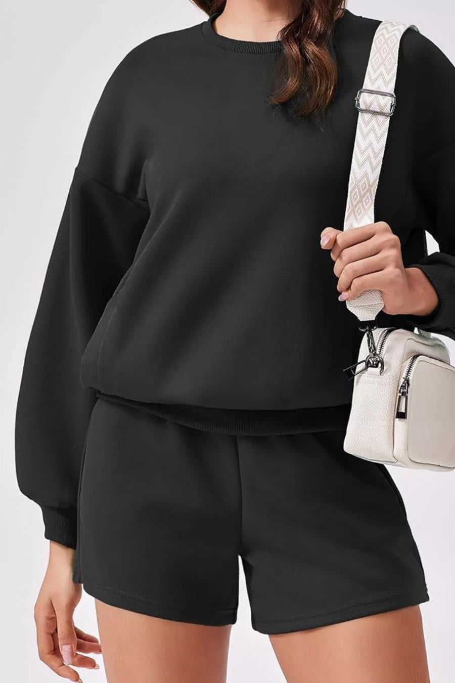 Black two-piece sweatshirt set with crewneck sweatshirt and drawstring shorts.