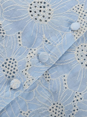 Light blue cotton shirt with white floral eyelet embroidery and fabric-covered buttons.