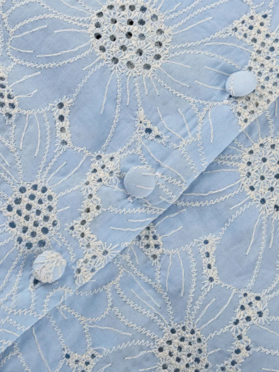 Light blue cotton shirt with white floral eyelet embroidery and fabric-covered buttons.