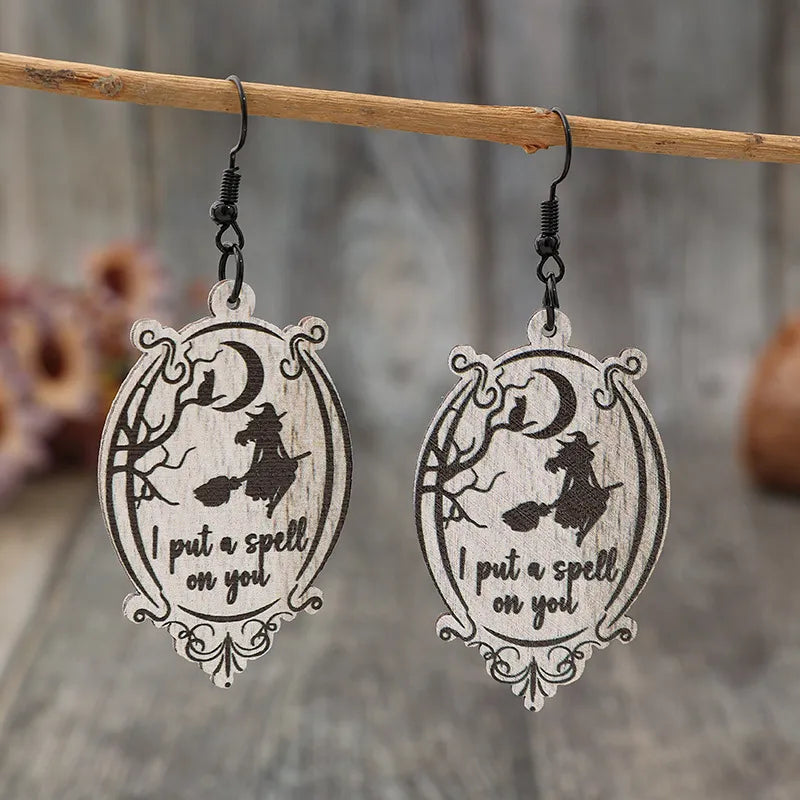 Black wood drop earrings with witch, cat, moon, and spell text.
