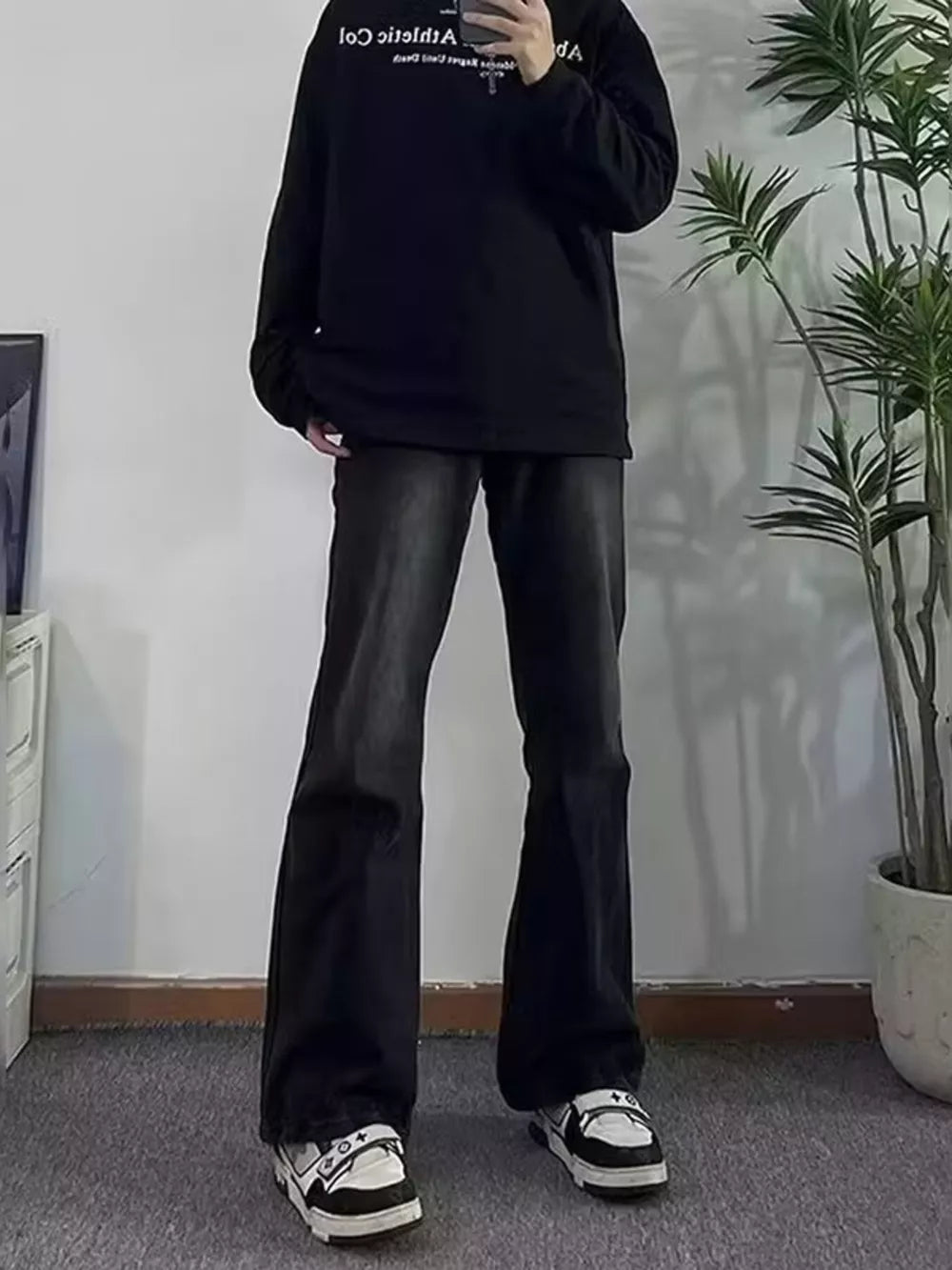 Men's dark wash cotton flare jeans with pockets, styled with a black sweatshirt and sneakers.