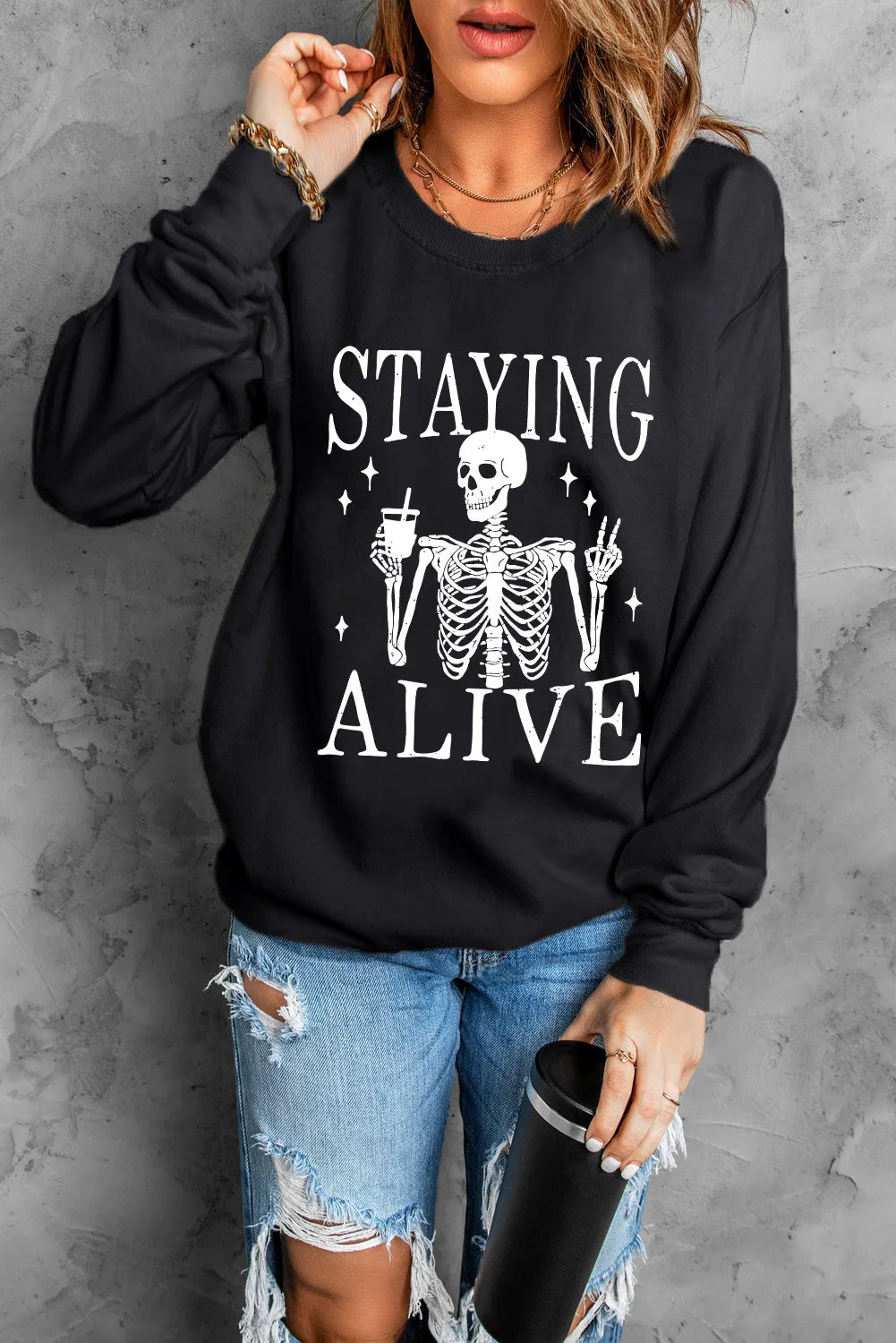 Black graphic sweatshirt with skeleton and "Staying Alive" text, crew neck, long sleeves.