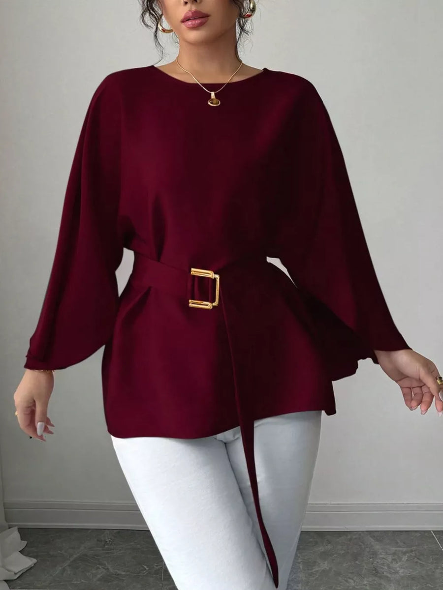 Wine red belted blouse with batwing sleeves and gold buckle detail.