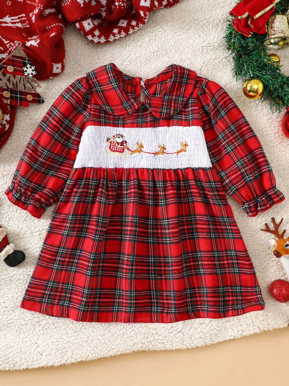 Red plaid baby dress with smocked Santa and reindeer detail, long sleeves, and Peter Pan collar.