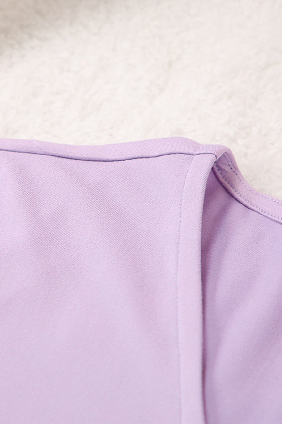 Draped wrap top detail in soft lilac purple fabric with clean stitching.