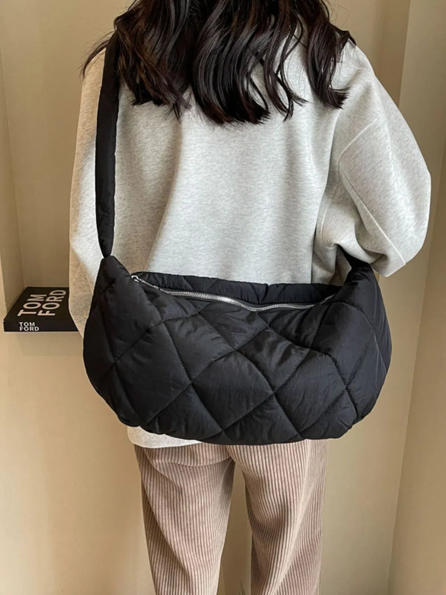 Black quilted crossbody bag with diamond pattern and silver zipper detail.