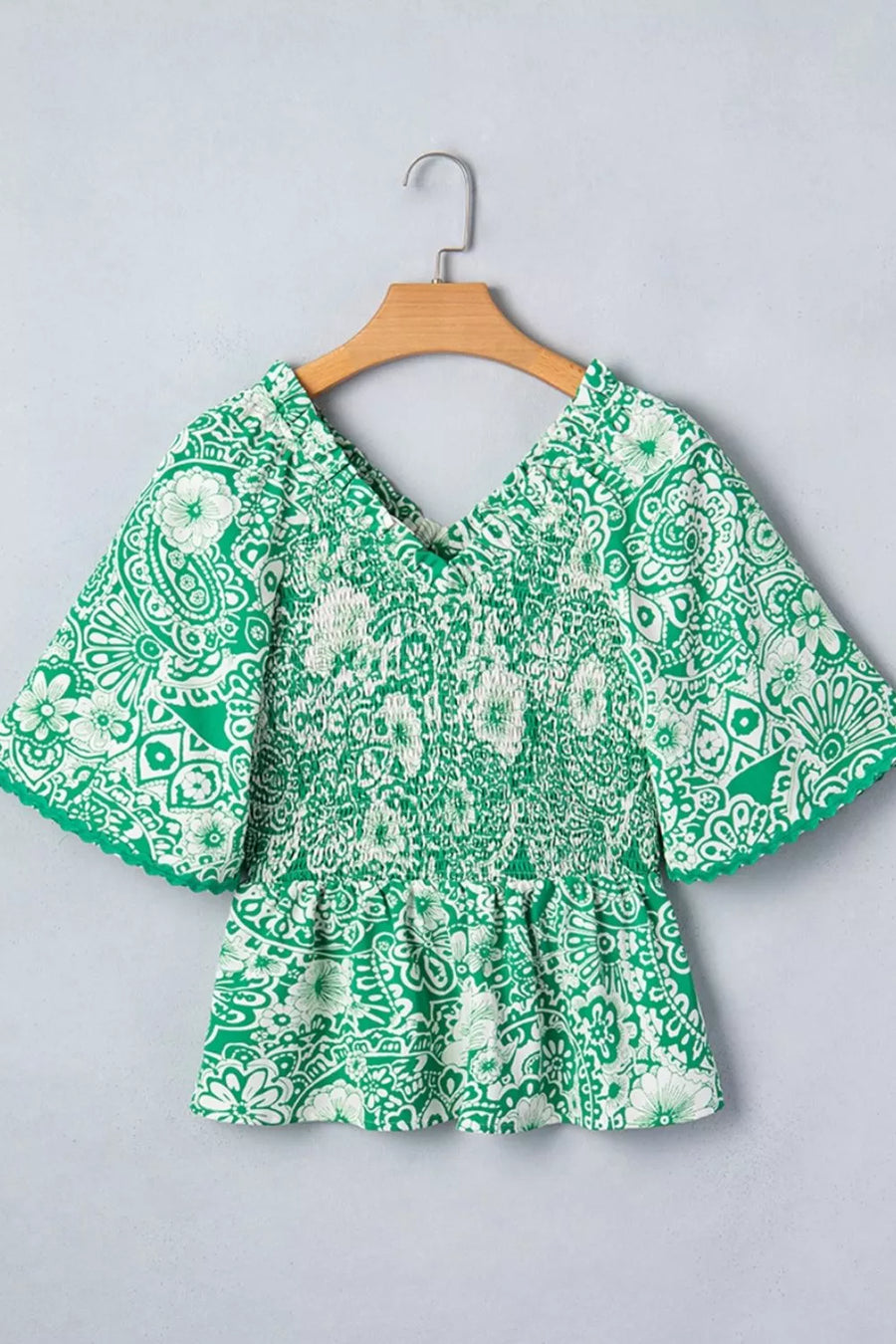 Green floral smocked v-neck polyester overshirt with ruffled sleeves.