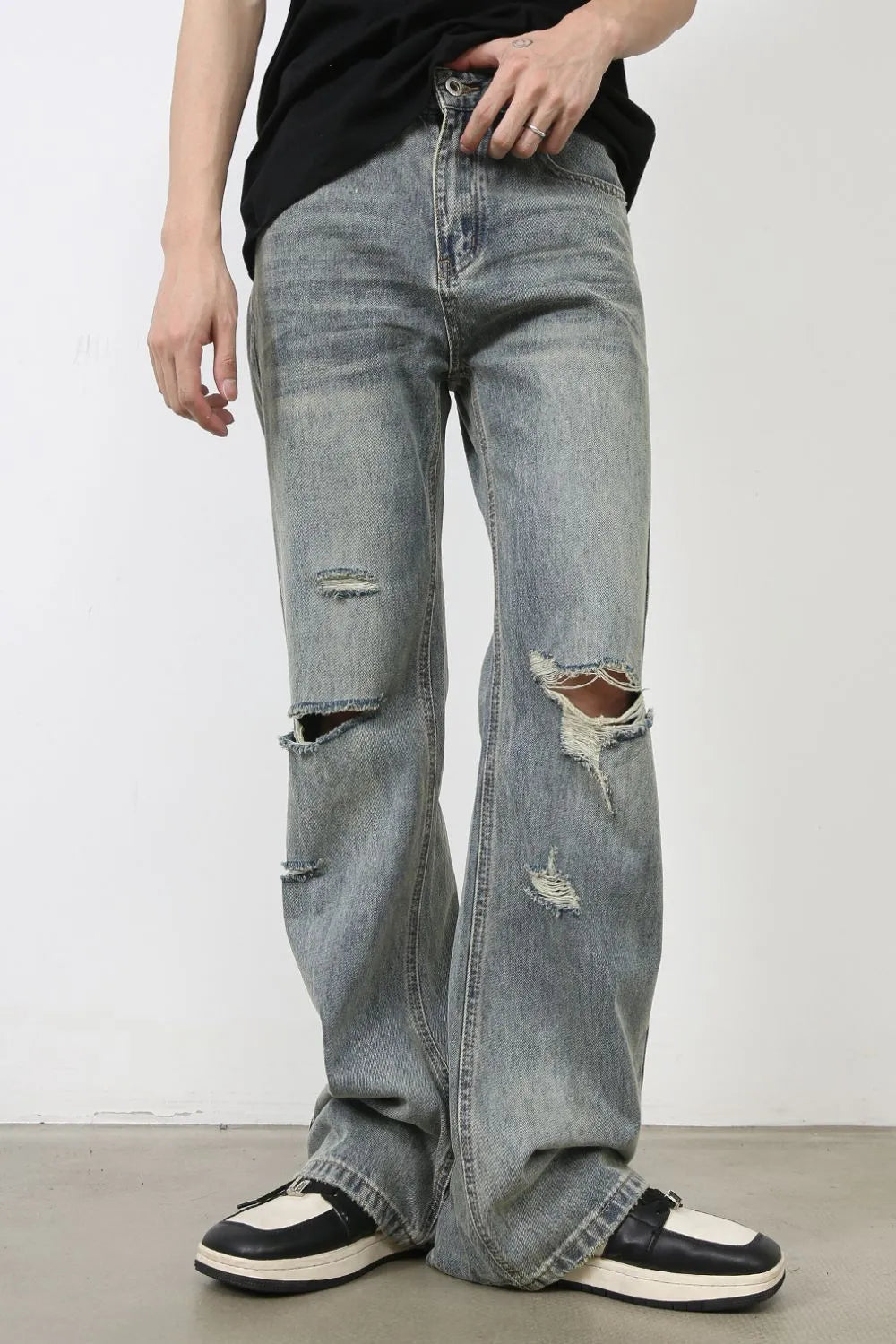 Distressed flare jeans in medium wash denim with raw-cut knee details and a relaxed fit.