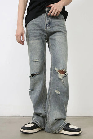 Distressed flare jeans in medium wash denim with raw-cut knee details and a relaxed fit.
