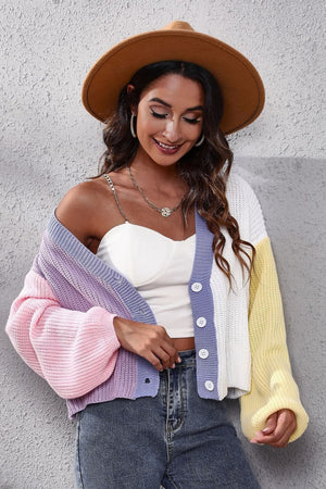 Panelled ribbed knit cardigan in pastel pink, lavender, white, and yellow with balloon sleeves and button front.