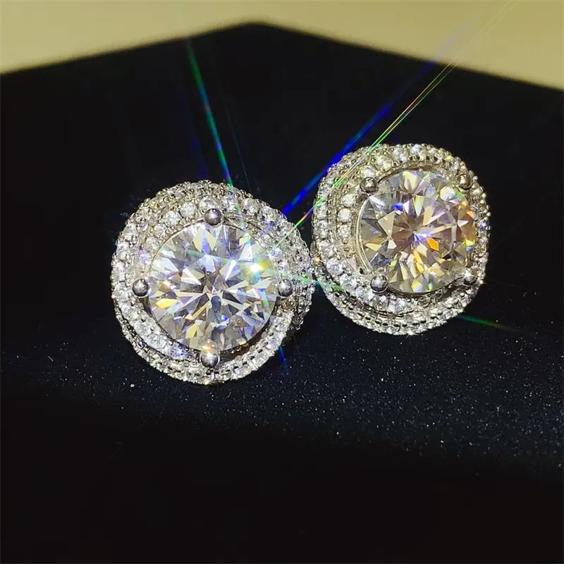 Halo diamond cluster stud earrings in silver with a central round-cut stone surrounded by smaller stones.