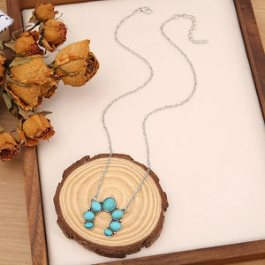 Turquoise horseshoe necklace with silver chain, featuring multiple oval and round turquoise stones.