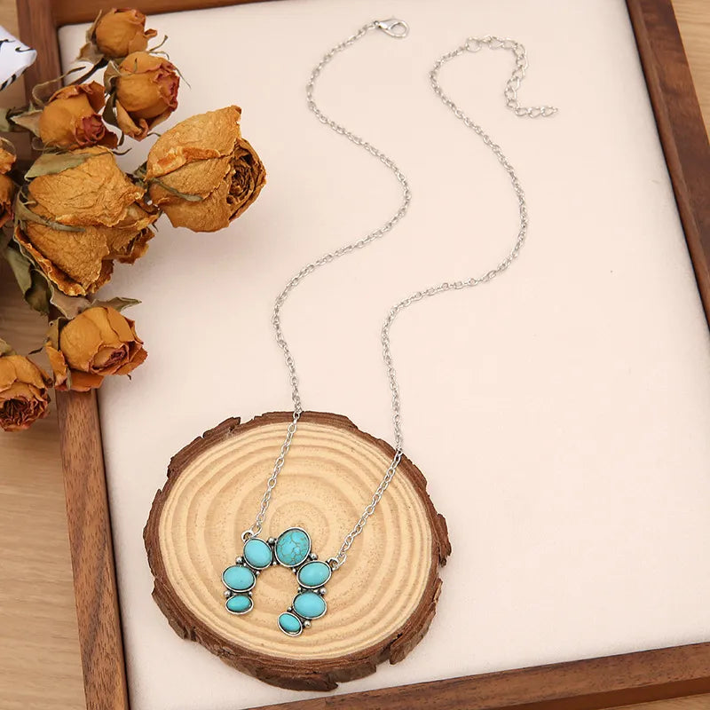 Turquoise horseshoe necklace with silver chain, featuring multiple oval and round turquoise stones.