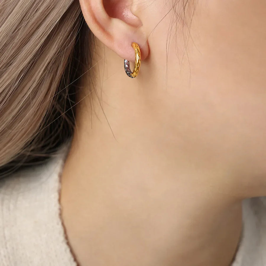 Textured two-tone gold huggie hoop earrings with a hammered finish.