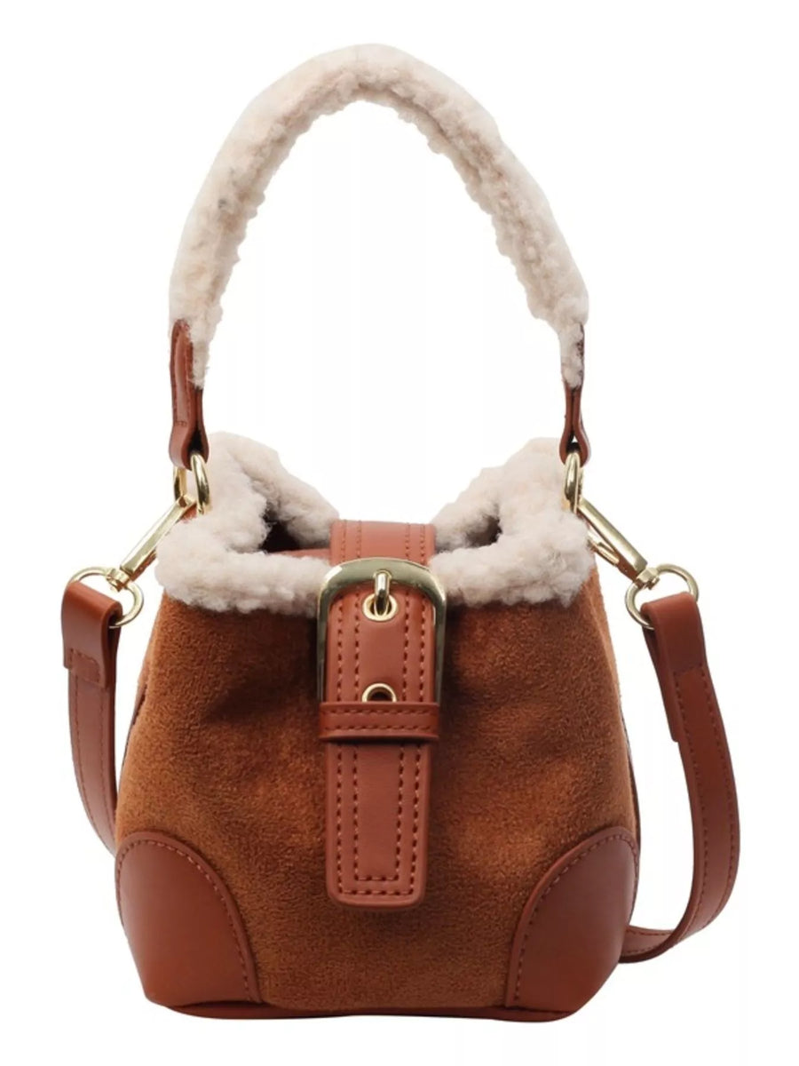 Brown suede bucket bag with fuzzy trim and buckle detail, crossbody strap.