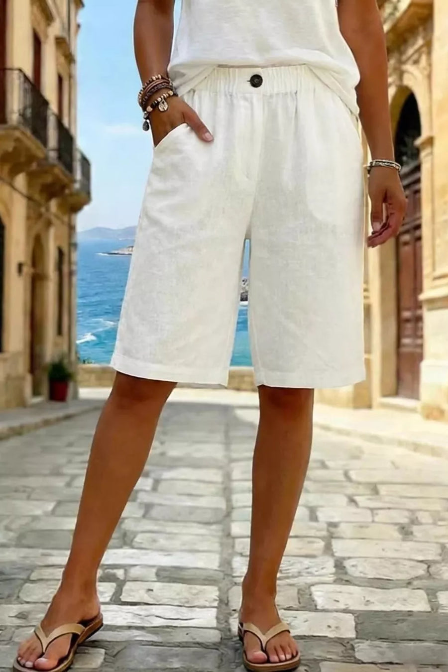 White linen shorts with pockets and elastic waist, knee-length.